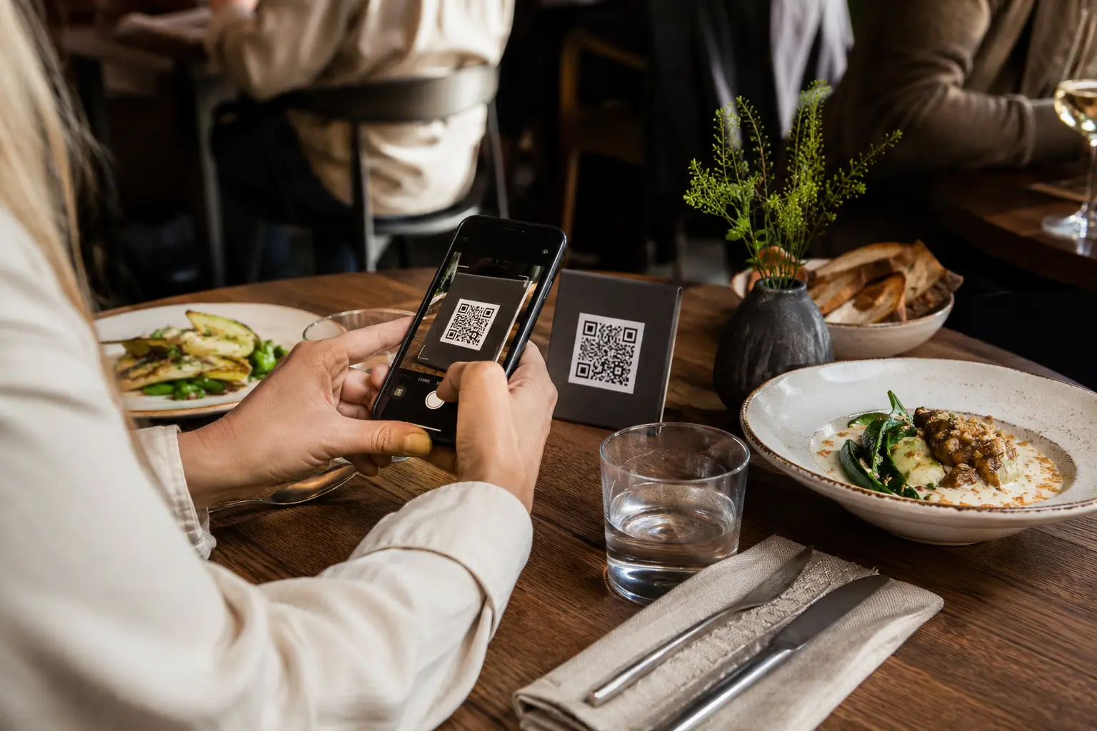 Restaurantgast scannt einen QR-Code am Tisch mit dem Smartphone